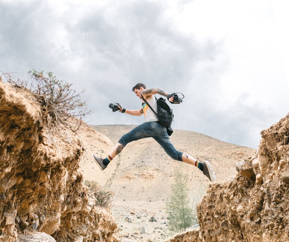 active man jumping over rocky formations